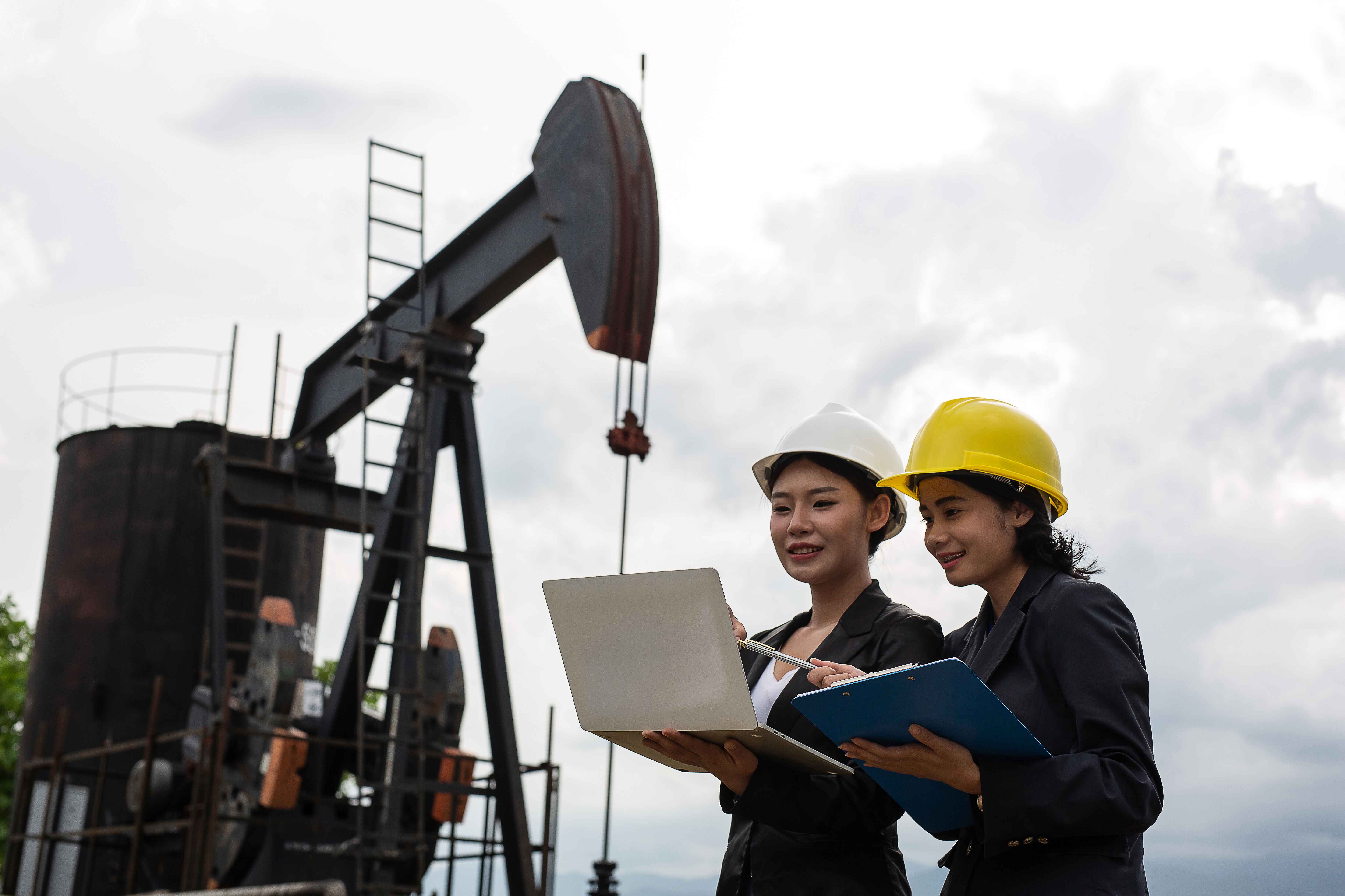 two-female-engineers-stand-beside-working-oil-pumps-with-white-sky (2) (1).jpg